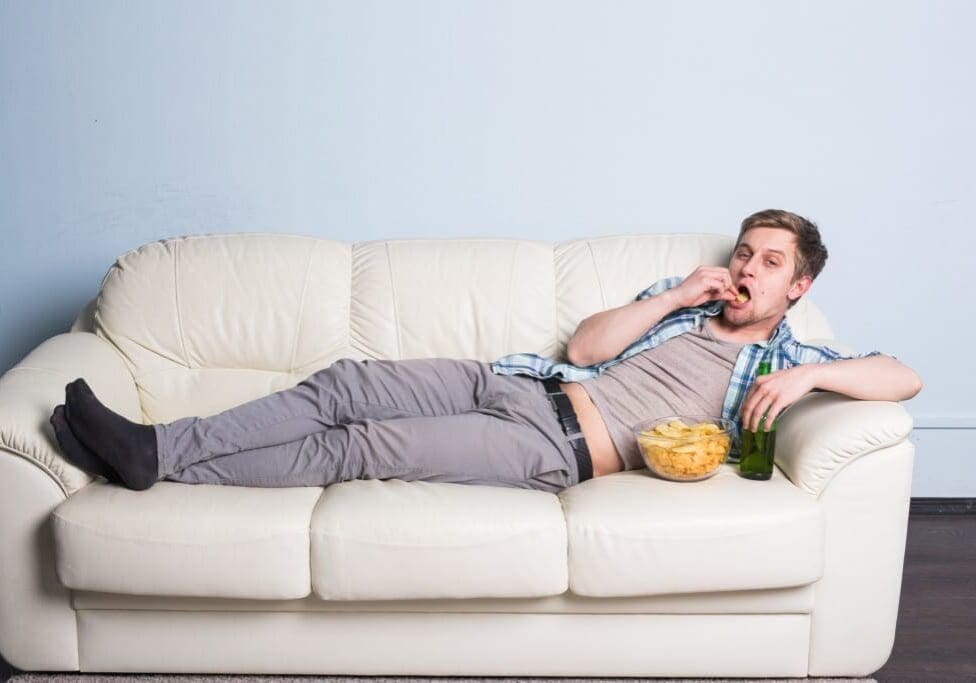 Man with beer and chips watching TV at home.