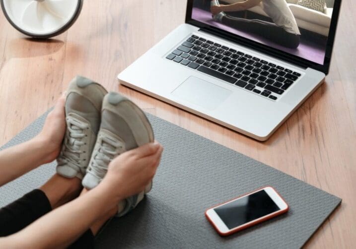 Flexibility and strength. Fit young woman stretching muscles at home, doing exercises while watching yoga tutorial online on laptop. Fitness and home yoga concept